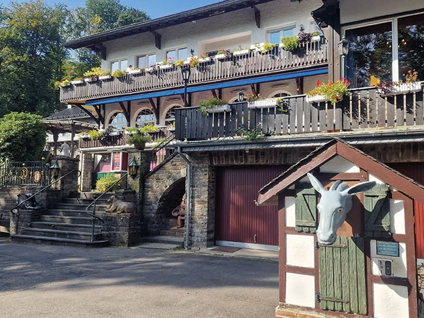 Märchenwald Fachwerkgebäude mit Blumenschmuck, Steintreppen und einer markanten Eselfigur im Vordergrund.