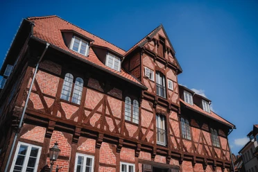 Lüner Mühle Historische Lüner Mühle: Fachwerkhaus aus rotem Backstein mit dunklen Balken vor blauem Himmel.