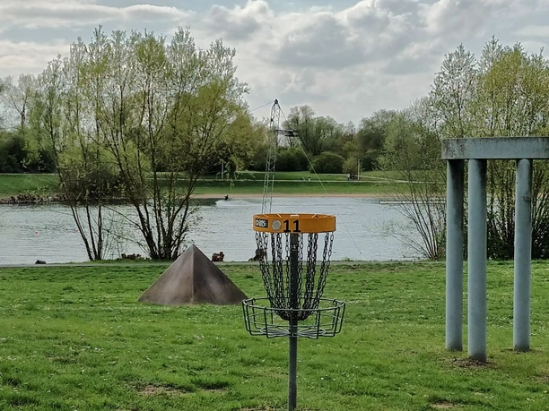 Ein Discgolf-Korb auf einer grünen Wiese direkt am Ufer des Salzgittersees.