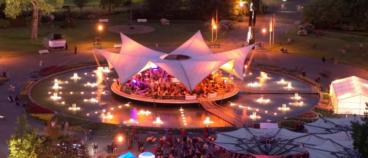 Tanzbrunnen Köln Beleuchtete Open-Air-Bühne im Park mit Wasserfontänen und dicht gedrängtem Publikum.