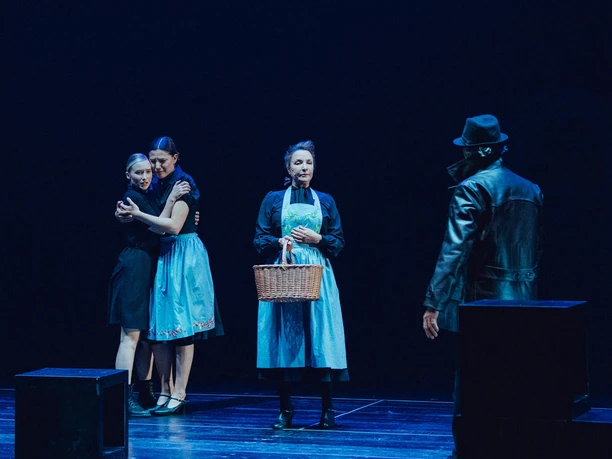 Die Weiße Rose, Magdalena Scholl Bühnenmoment mit zwei sich umarmenden Frauen, einer Frau mit Korb und einem Mann im Mantel.