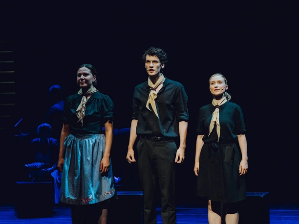 Die Weiße Rose, Hans, Sophie Inge Drei Darstellende in dunkler Kleidung stehen auf einer Bühne und singen im Scheinwerferlicht.