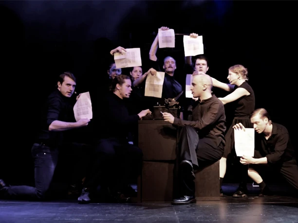 Die Weiße Rose Gruppe in dunkler Kleidung auf Bühne hält Blätter hoch um eine Schreibmaschine