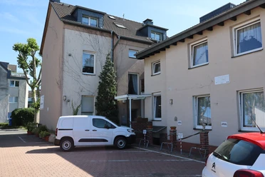 Gästewohnungen Koch in Ratingen Außenansicht der Gästewohnungen Koch in Ratingen mit zwei Gebäuden und Parkplatz.