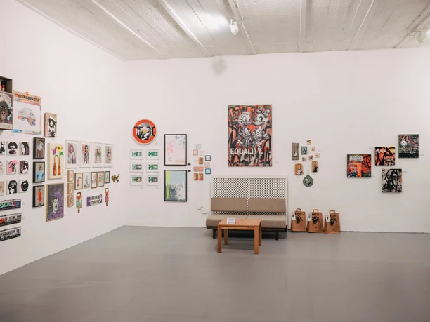 Urban Wildcard Art im Studio 40 Köln Helle Galerie mit vielen modernen Bildern an weißen Wänden und einer Sitzbank im Raum