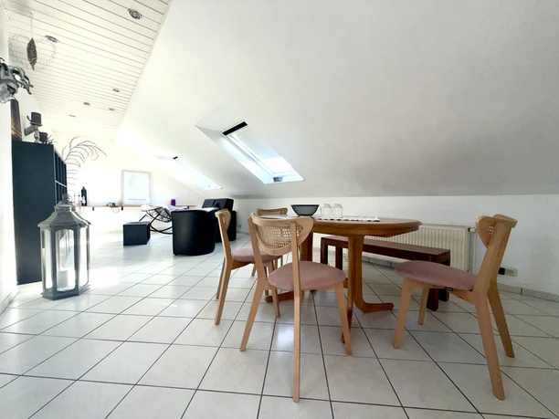 Ferienwohnung Langendamm Heller Wohn- und Essbereich einer Ferienwohnung mit Holztisch, Stühlen und dunklen Möbeln.