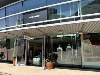 Eingang des Pegador Stores mit Glasfassade, großem Logo und Schaufensterpuppen.