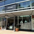 Eingang des Pegador Stores mit Glasfassade, großem Logo und Schaufensterpuppen.