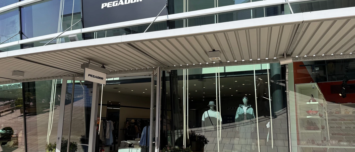 Pegador Outlet Shop Eingang des Pegador Stores mit Glasfassade, großem Logo und Schaufensterpuppen.