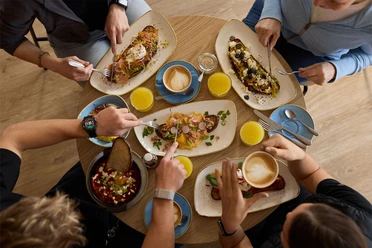 Café FRIDA in Büsum Vier Personen sitzen an einem Tisch und Essen.
