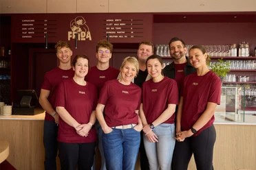 Das Team vom Café FRIDA in Büsum Acht Personen vor einem Tresen in roten Shirts.