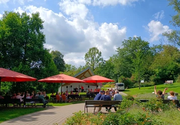Kurkonzert im Kurpark Eckenhagen Open-Air-Konzert im Park mit Bühne, roten Sonnenschirmen und Publikum auf Bänken