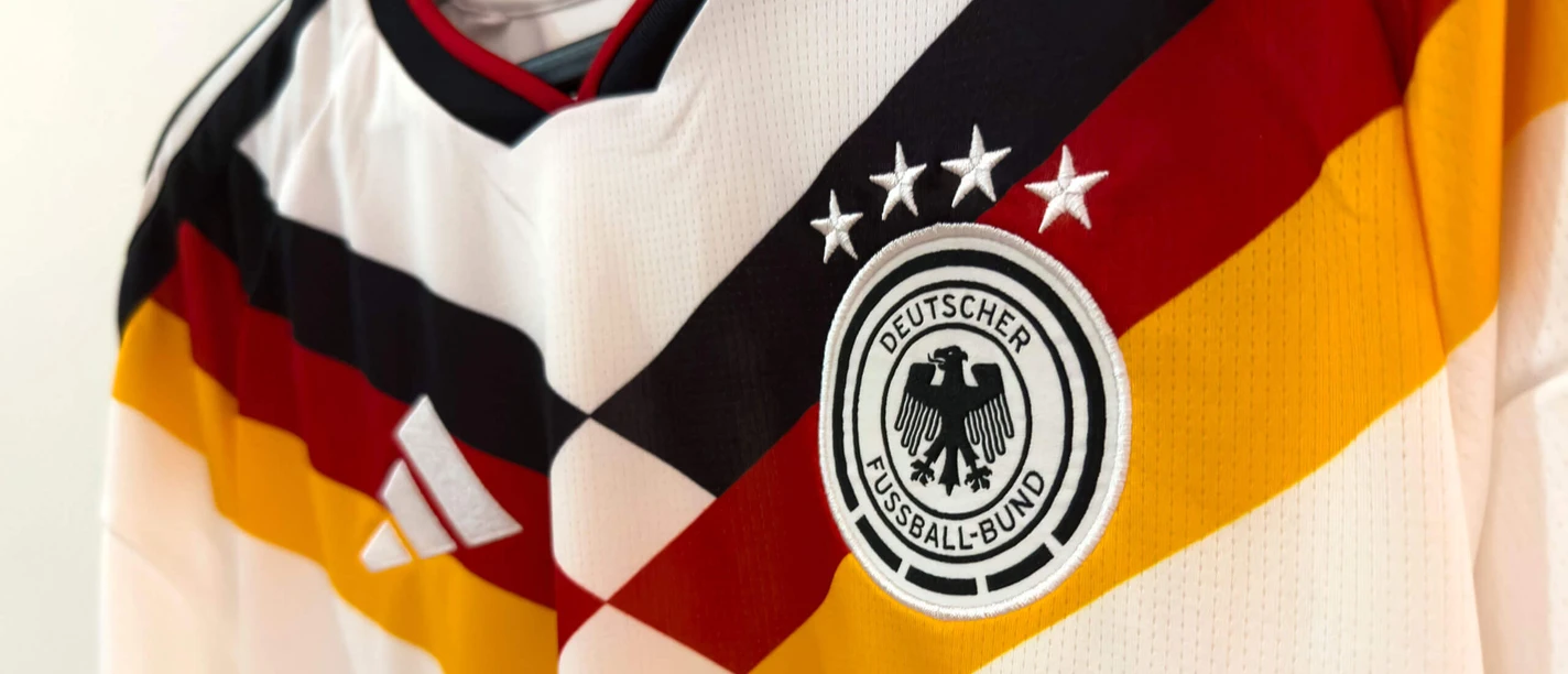 Trikot der deutschen Nationalmannschaft Weißes Fußballtrikot mit schwarz-rot-goldenem Muster und DFB-Emblem mit vier Sternen