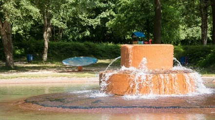 IMG_72171527575500_WEB.jpg Wasserspielbereich im Spielpark Leherheide, umgeben von Bäumen