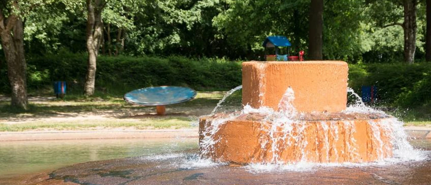 IMG_72171527575500_WEB.jpg Wasserspielbereich im Spielpark Leherheide, umgeben von Bäumen