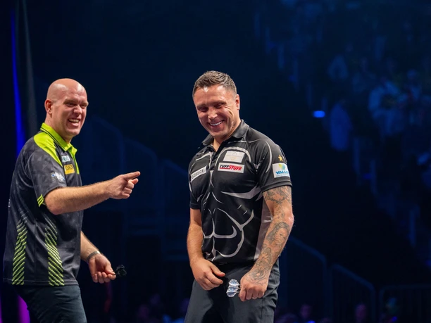 Winamax Cologne World Darts Gala Two dart players laugh together on the stage of a brightly lit arena.