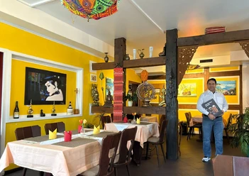 lion-restaurant.jpg Innenraum eines indischen Restaurants mit gelben Wänden, gedeckten Tischen und Inhaber
