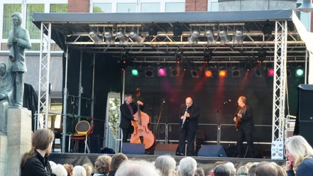 2014_Klesmerfestival_HD_16zu9.JPG Drei Musiker mit Kontrabass, Klarinette und Gitarre auf einer Bühne vor Publikum.