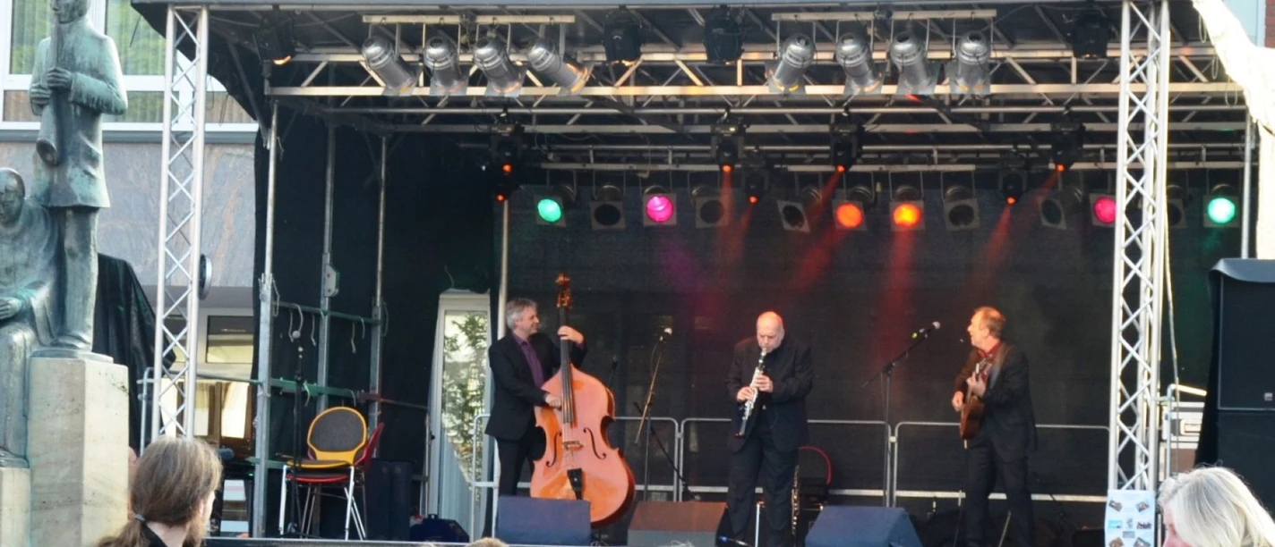 2014_Klesmerfestival_HD_16zu9.JPG Drei Musiker mit Kontrabass, Klarinette und Gitarre auf einer Bühne vor Publikum.