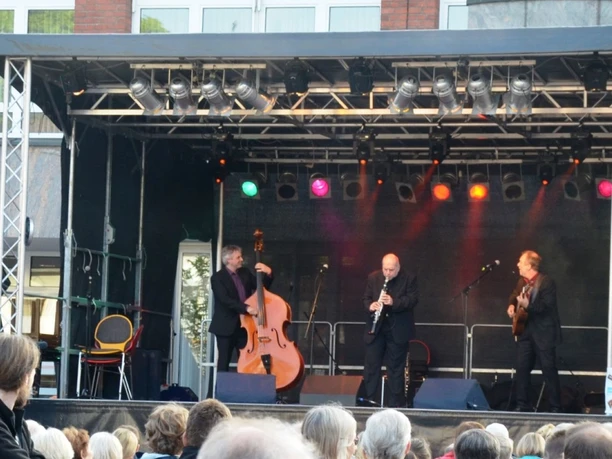 2014_Klesmerfestival_HD_16zu9.JPG Drei Musiker mit Kontrabass, Klarinette und Gitarre auf einer Bühne vor Publikum.