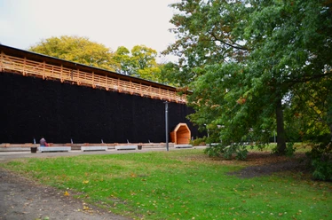 Gradierwerk im Lüneburger Kurpark Langes Gradierwerk aus dunklem Reisig mit Holzdach im Kurpark neben Bäumen.