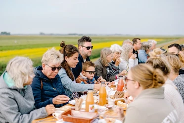 Frühstück am Deich in Friedrichskoog Personen unterschiedlichen Alters sitzen gemütlich zum Frühstück am Deich