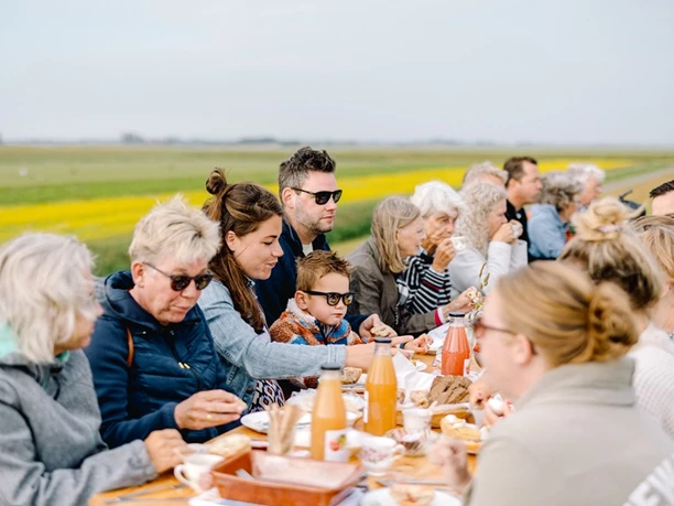 Frühstück am Deich in Friedrichskoog Personen unterschiedlichen Alters sitzen gemütlich zum Frühstück am Deich