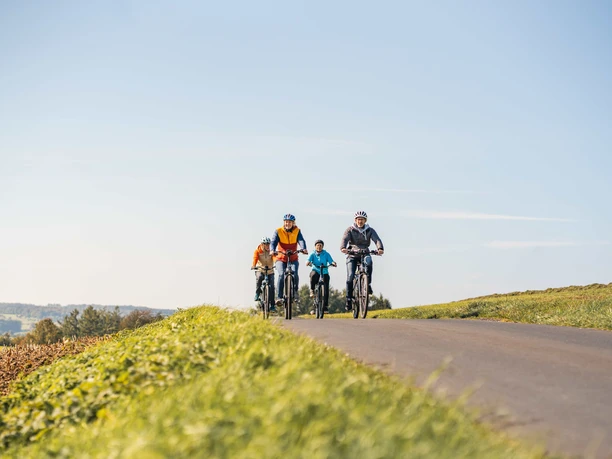 Radtour im Bergischen Vier Radfahrende rollen auf einer ländlichen Straße bei klarem Himmel durch offene Felder