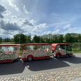 Bimmelbahn-Weser-Huxarium Gartenpark Höxter gGmbH.jpg Bimmelbahn am Weserufer in Höxter mit Blick auf Fluss
