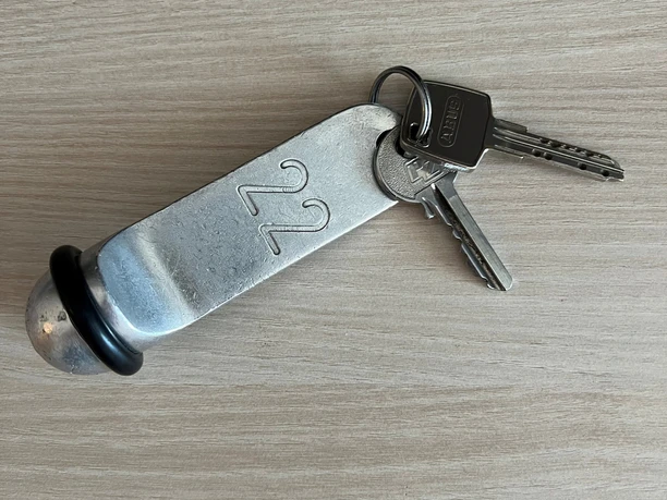 Hotelschlüssel Zwei Schlüssel an einem massiven Metallanhänger mit der Nummer 22 auf hellem Holz.