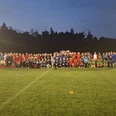 20250718_222232.jpg Fußballmannschaften posieren abends auf dem beleuchteten Rasenplatz für ein Gruppenfoto.