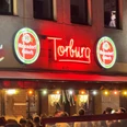 Die Torburg in der Südstadt Nächtliche Barfassade mit rotem Torburg-Neonlicht und dichtem Andrang vor dem Eingang