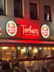 The Torburg in the Südstadt Night-time bar façade with red Torburg neon light and dense crowds in front of the entrance