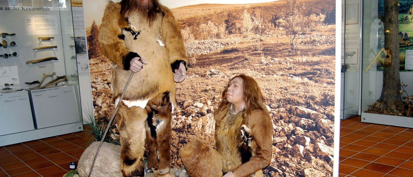 Ausstellung_Neandertaler_Salder_HD_16zu9.jpg Zwei lebensgroße Neandertaler-Figuren in Tierfellen vor einem Landschaftsbild im Museum.