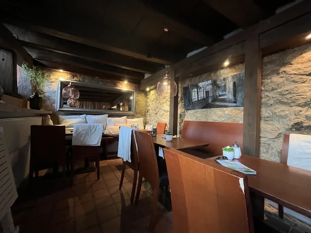 Café Bohne Gastraum mit Holzbalken, Steinwänden, Tischen und Sitzbänken im Café Bohne