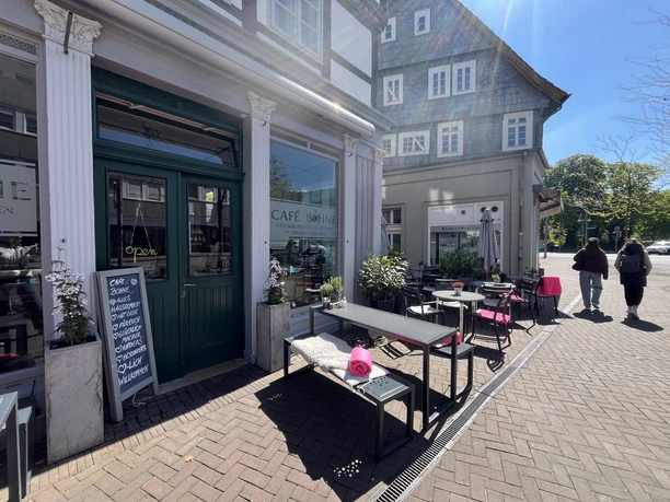 Außengastronomie vor Café Bohne, grüne Tür, Tafel und Tische im Sonnenlicht