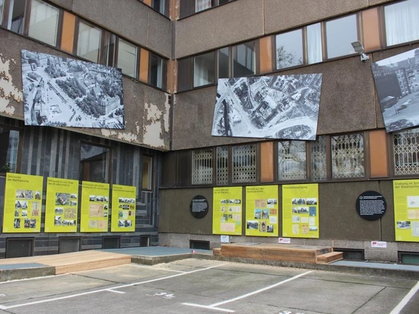 Výstava pod širým nebem "Od hradu k sídlu Stasi" s velkoformátovými informačními tabulemi a historickými fotografiemi, které jsou umístěny podél fasády budovy a názorně představují historii Matthäikirchhofu.