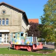 Bahnhof Salzgitter-Bad aus Stein. Davor steht eine bunte Lokomotive.