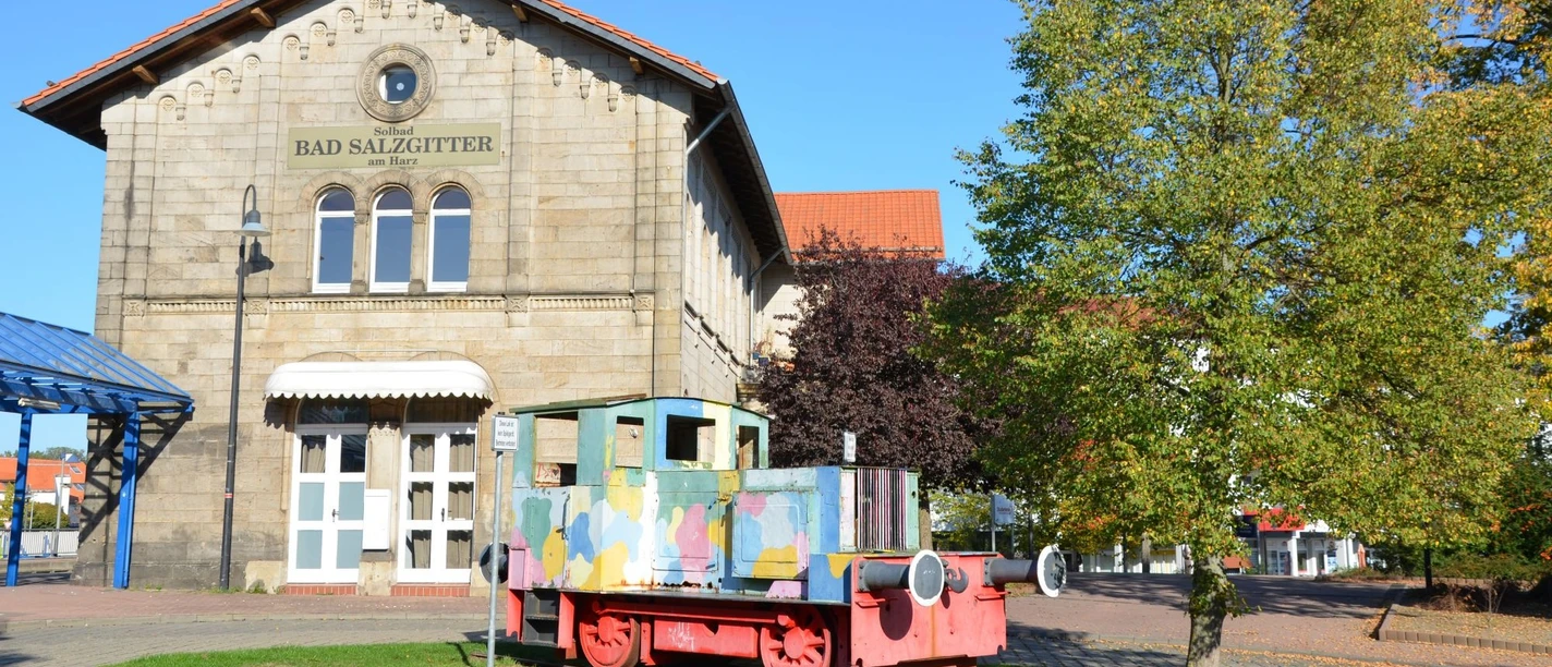 Bahnhof_SZ-Bad_HD_16zu9.JPG Bahnhof Salzgitter-Bad aus Stein. Davor steht eine bunte Lokomotive.