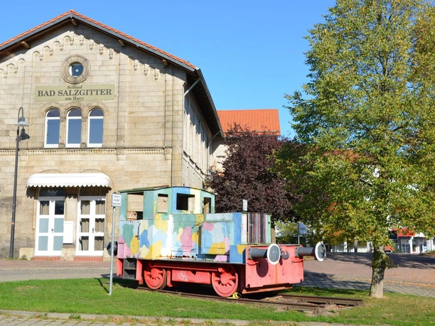 Bahnhof_SZ-Bad_HD_16zu9.JPG Bahnhof Salzgitter-Bad aus Stein. Davor steht eine bunte Lokomotive.
