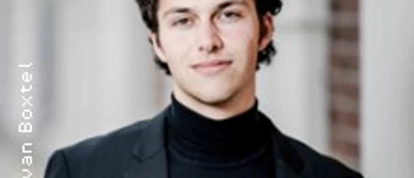 Junger Mann mit lockigem Haar in schwarzem Turtleneck vor hellem unscharfem Hintergrund