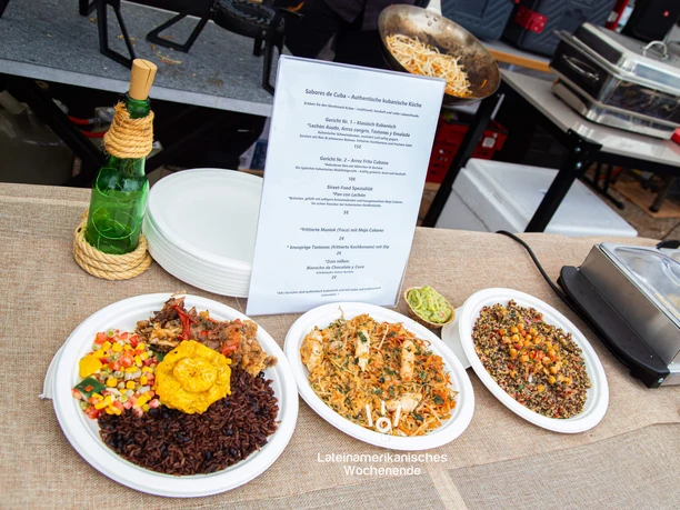 Latin American weekend at the Südbrücke Cologne Colorful Latin American dishes on plates at a festival stand with a visible menu board.
