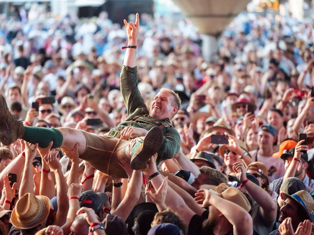 Original Egerländer Festival am Kölner Tanzbrunnen Mann in Tracht wird jubelnd auf Händen einer dicht gedrängten Menge getragen.