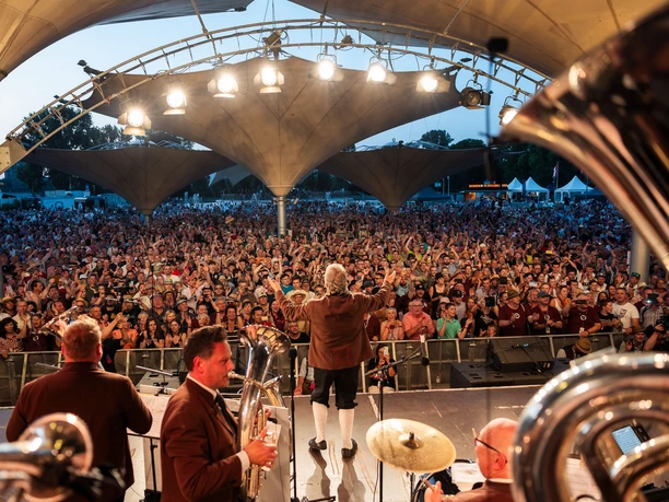 Original Egerländer Festival am Kölner Tanzbrunnen Blick von der Bühne auf eine große jubelnde Menge bei einem Open-Air-Konzert am Abend