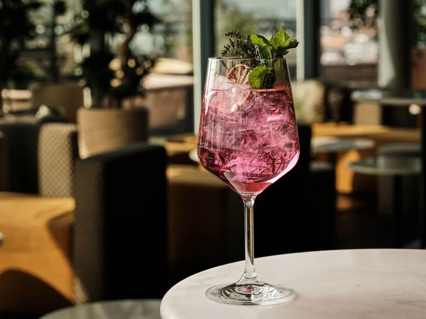 Bar Botanik - Signature Drink Rosa Cocktail im Weinglas auf einem Tisch in einer modernen Barumgebung.
