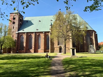 Dom Verden Großer Backsteindom mit grünem Dach und Turm. Davor Wiese und Bäume.