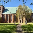 Dom Verden Großer Backsteindom mit grünem Dach und Turm. Davor Wiese und Bäume.