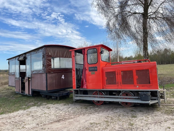 Red locomotive of the Uchter Moorbahn with brown wagon in a moor landscape.