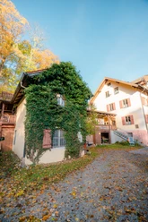 Tusculum @Tourist Information Murnau.jpg Das Bild zeigt das Christoph-Probst-Geburtshaus in Murnau.. Ein kleines Haus mit Efeu neben einem größeren Gebäude an einem herbstlichen Hof.