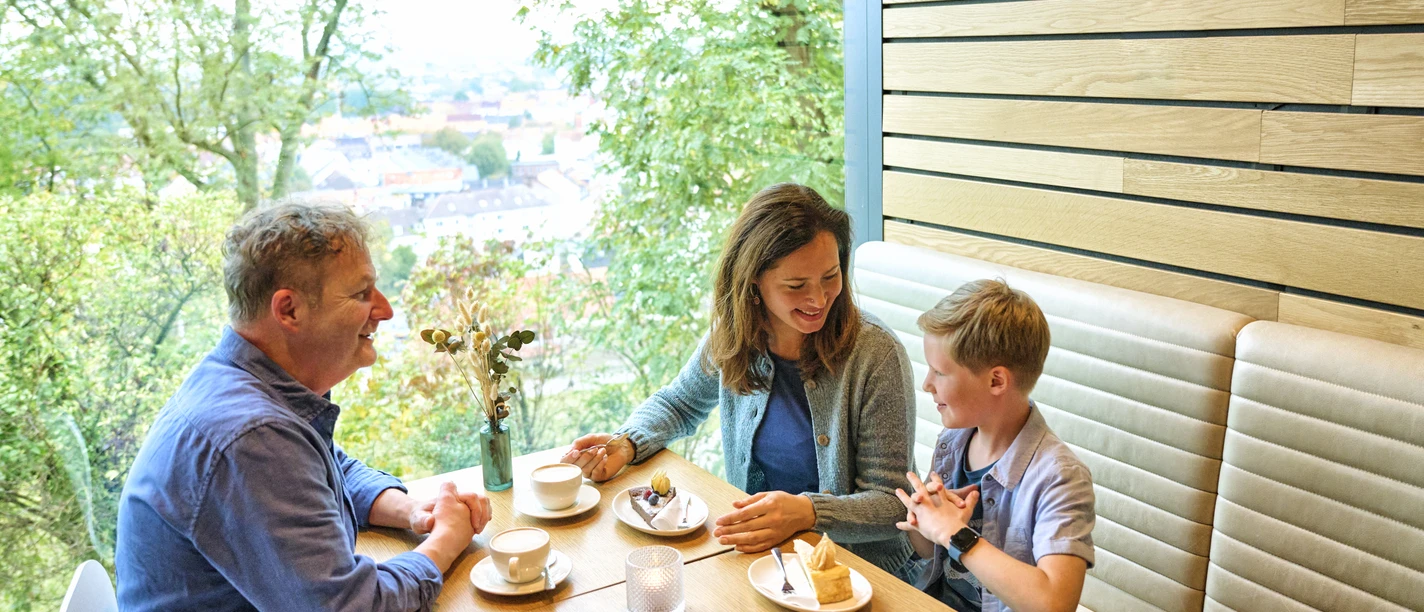 Eine Familie sitzt am Tisch bei Kaffee und Kuchen.